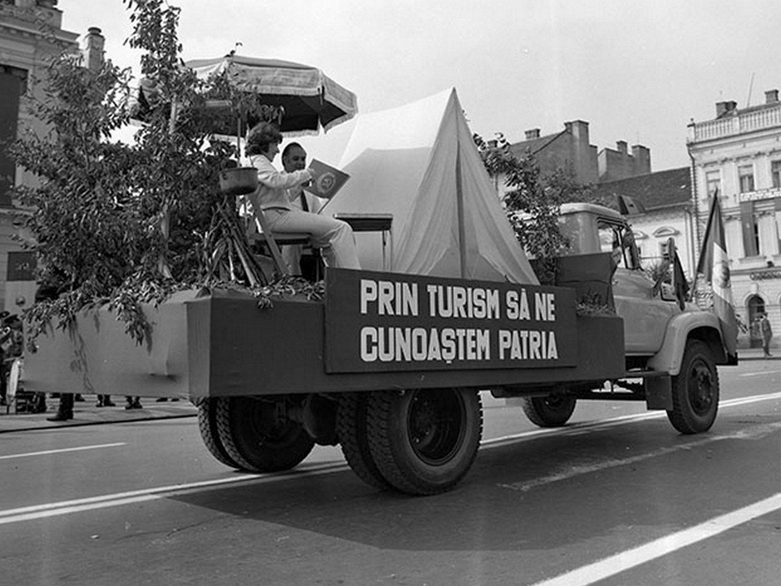 Culmea absurdului - un camion în care e un cort, o tufă, o umbrelă, un ceaun și doi pseudo-turiști, el având cravată, promovează turismul.