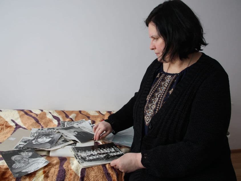 Yuliya, refugiată din Ucraina, răsfoiește prin fotografiile pe care a reușit să le ia cu ea atunci când a fugit de război. Foto: Mike Bruce