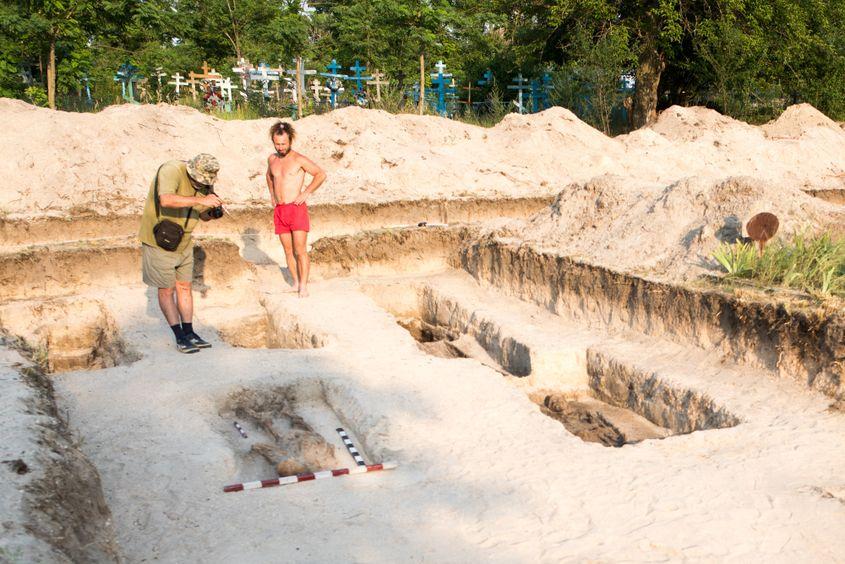 Gheorghe Petrov, cu aparatul de fotografiat, la mormintele unor oameni uciși la Periprava. În dreapta, arheologul Paul Scrobotă. Foto: Raul Ștef