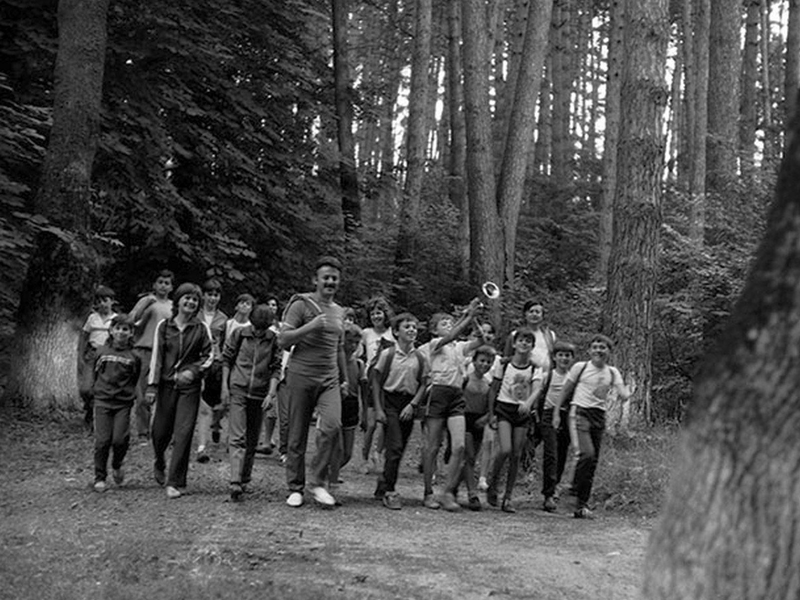 Pionieri aflați în tabără într-o excursie prin pădure și sunet de trompetă