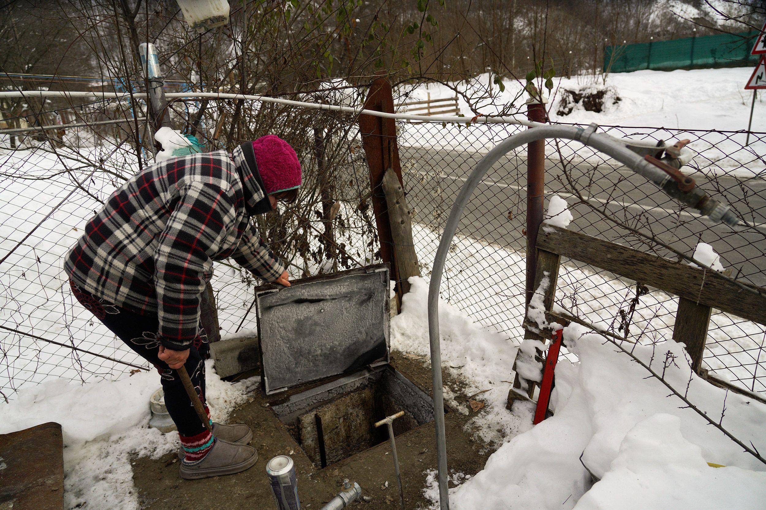 O femeie verifică starea hidroforului din curte, care nu funcționează în lipsă de curent electric. Foto: Raul Ștef