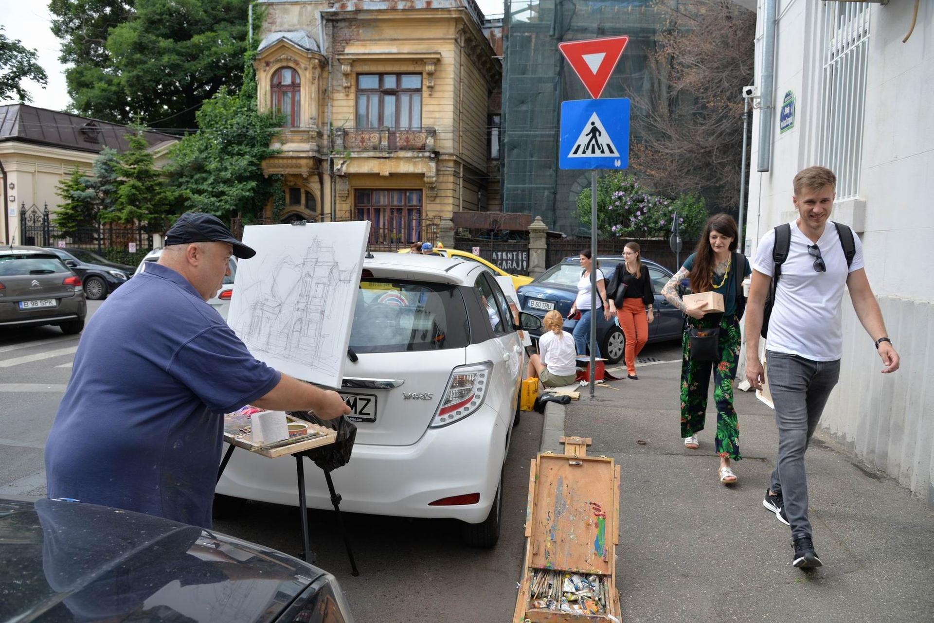 Vitalie Butescu pictează între mașini pe strada Ion Luca Caragiale din București. Foto Lucian Muntean