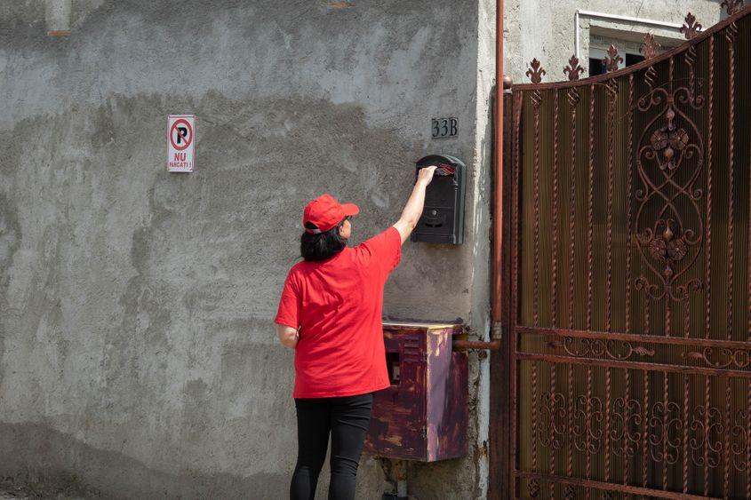 O doamnă înfige un pliant cu Pandele într-o cutie poștală. Foto: Mircea Pătrașcu