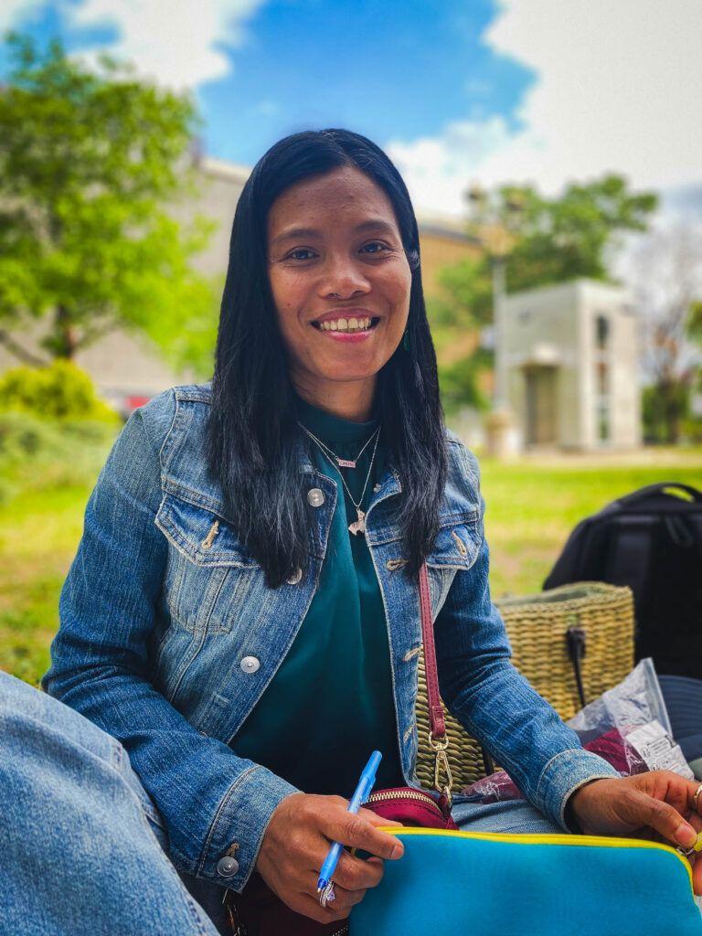 Divina este din Filipine și a venit în România în 2013. A venit la picnic cu un troler de avion portocaliu, un rucsac și o geantă de plajă. Foto: Luiza Popovici