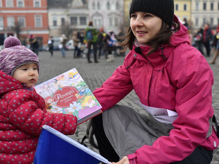 3 februarie: o mamă protestează în centrul Clujului alături de fetița ei, care ține în mână o Carte de povești de adormit copiii.
Fotografii: Raul Ștef