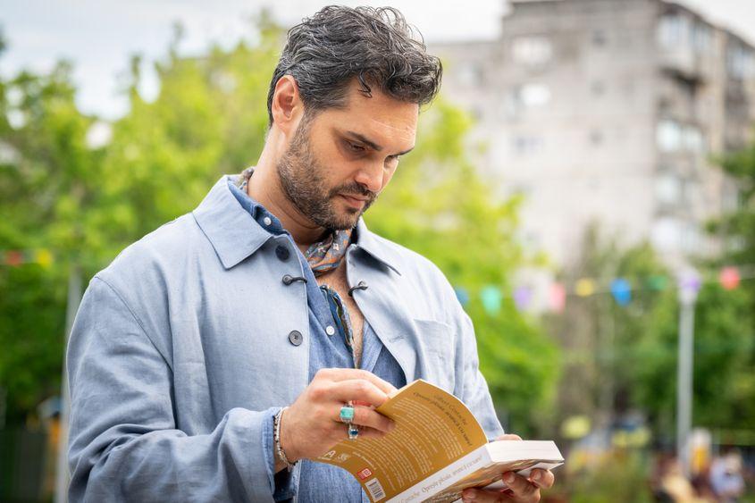 Gilbert Costache răsfoind propria sa carte „Oprește ploaia, aruncă cu sare!” Foto: Mihai von Eremia