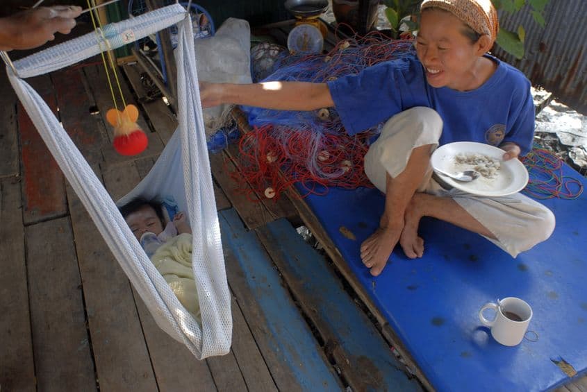 Mic dejun cu orez şi bebeluş fericit într-un sat pescăresc.