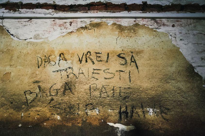 „Dacă vrei să trăiești, bagă paie sub haine” – scrie pe un zid de la Jilava.