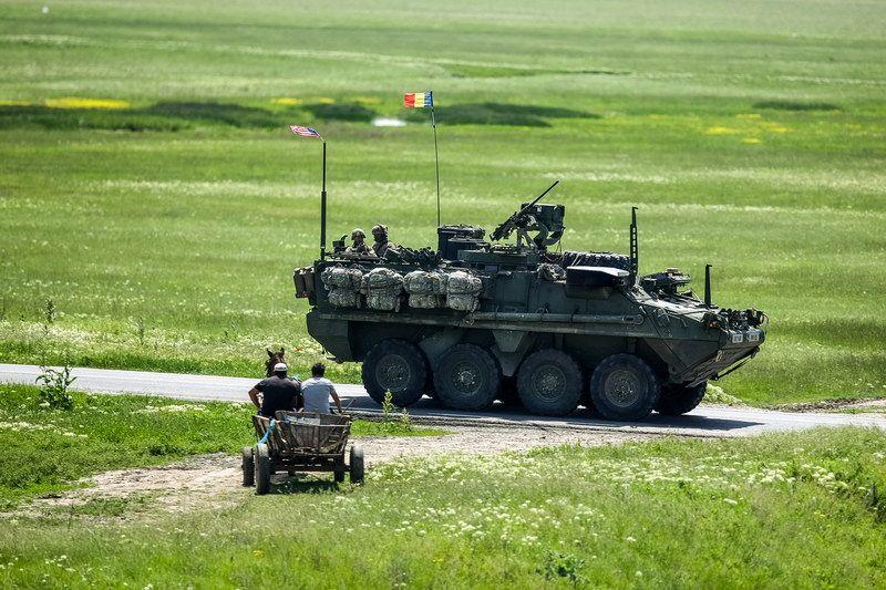 „O căruță așteaptă trecerea unei coloane de vehicule militare Stryker, aparținând armatei SUA, în România, miercuri 13 mai 2015.” <em>Inquam Photos / O</em>vidiu Micsik
